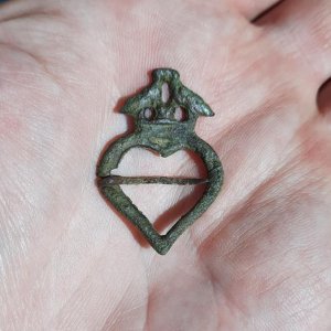 13th or 14th century annular brooch depicting 2 kissing birds over a heart